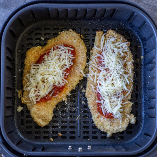 Chicken parmesan with marinara and cheese in an air fryer basket