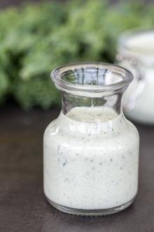 Ranch dressing in a jar with veggies around.