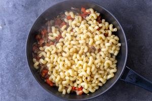 Pasta added to veggies in a pan