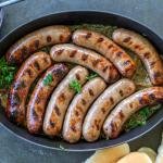 Bratwurst in a pan with onions, buns and chilin.