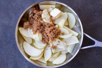 Apples with sugar and apple juice in a pan.