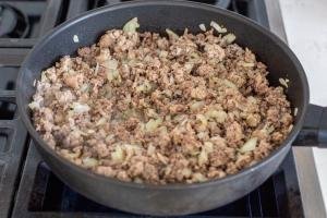 cooking meat with onion in a pan
