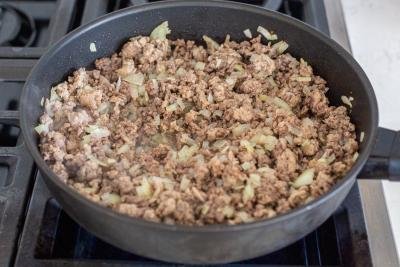 cooking meat with onion in a pan