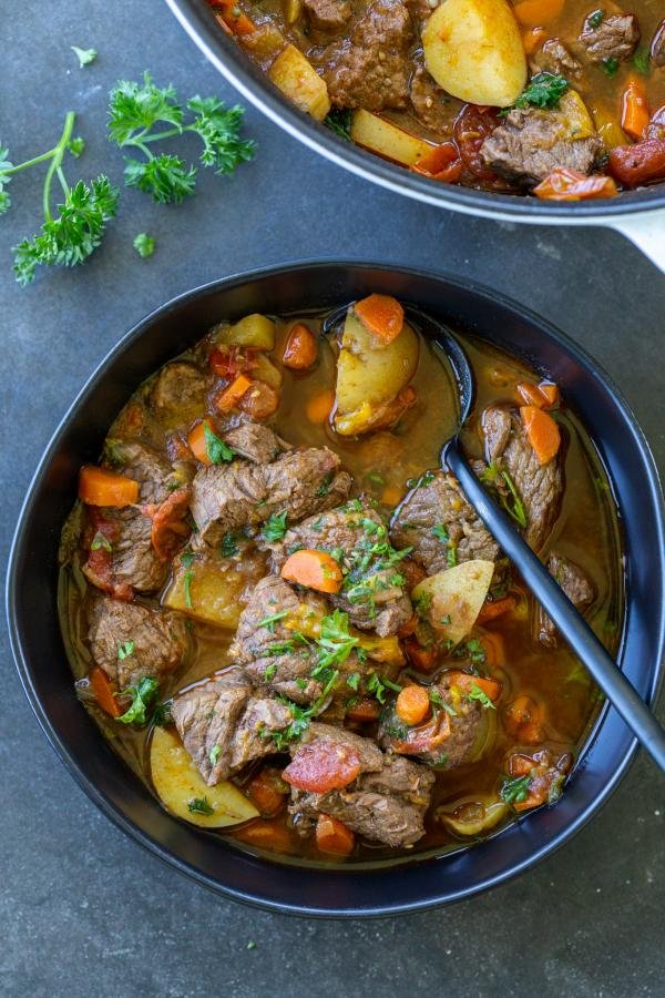 Shurpa soup in a bowl with a spoon and herbs. 