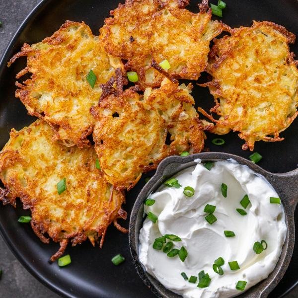 Cooked latkes on a plate with sour cream