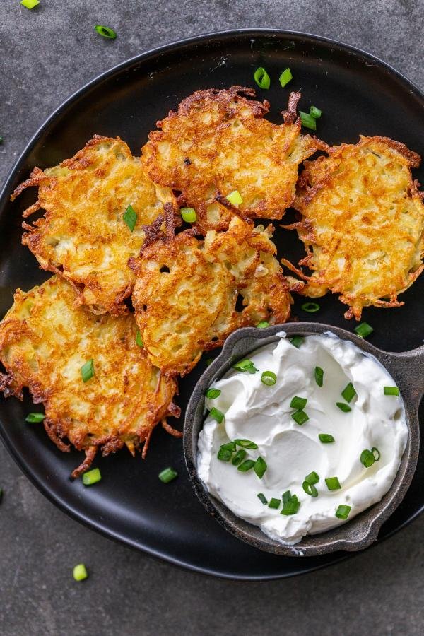 Cooked latkes on a plate with sour cream