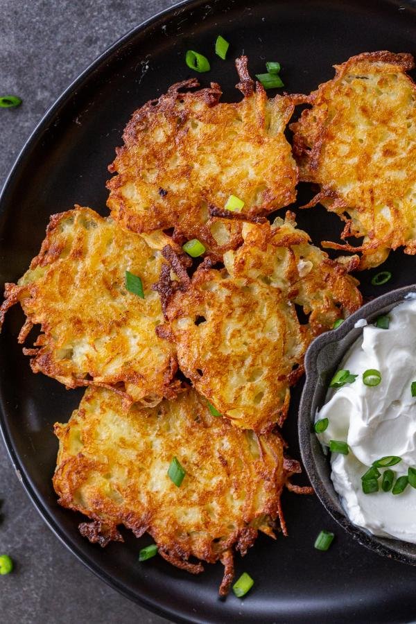 Cooked latkes on a plate with sour cream 