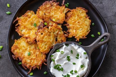 Cooked latkes on a plate with sour cream