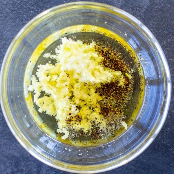 Garlic oil vinegar dressing in a bowl with salt and pepper