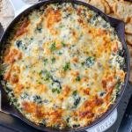 Baked spinach dip in a pan with crackers
