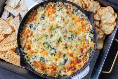 Baked spinach dip in a pan with crackers