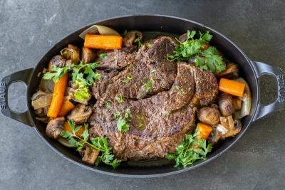 Slow cooked beef roast on a serving tray with veggies.