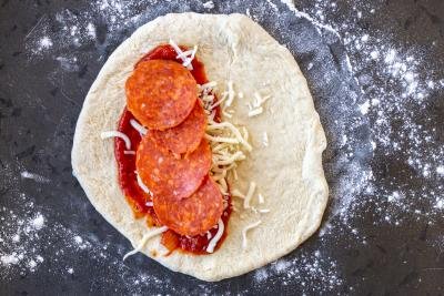 pizza dough with sauce and cheese and pepperoni