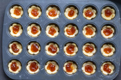 Dough in a pan with jam in the center.