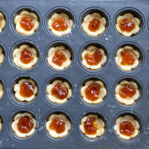 Dough in a pan with jam in the center.