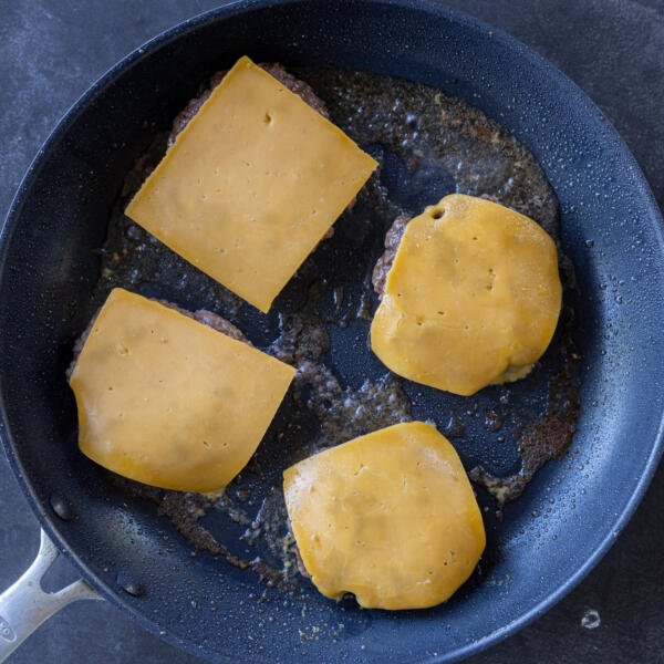 Beef patties in a pan with cheese on top,