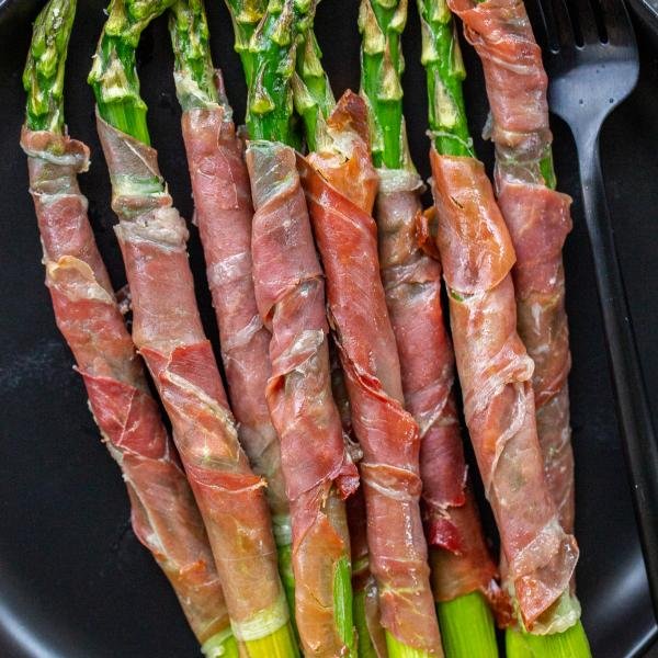 Baked Asparagus Wrapped in Prosciutto on a serving tray