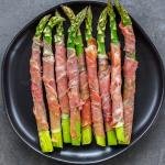 Baked Asparagus Wrapped in Prosciutto on a serving plate