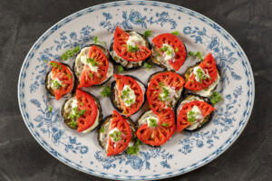 Plated Eggplant Appetizer with Tomato and herbs on top.