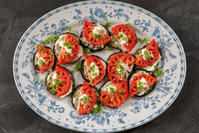 Plated Eggplant Appetizer with Tomato and herbs on top.