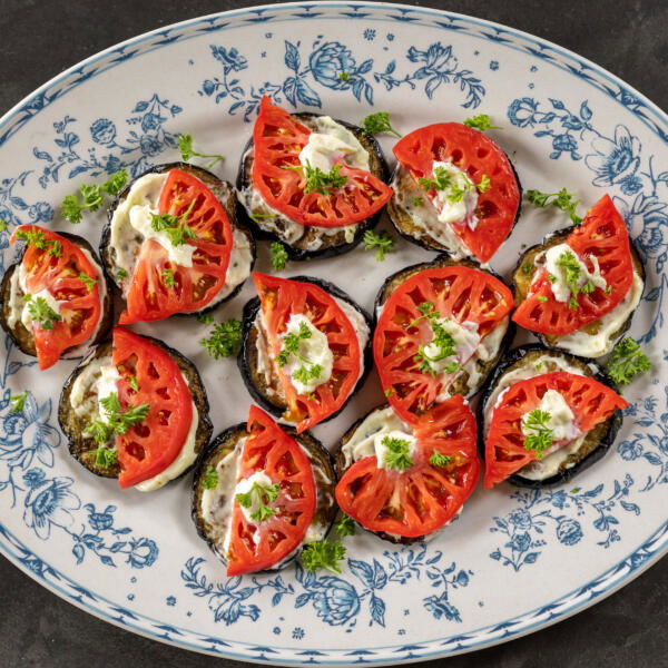Plated Eggplant Appetizer with Tomato and herbs on top.