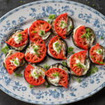 Plated Eggplant Appetizer with Tomato and herbs on top.