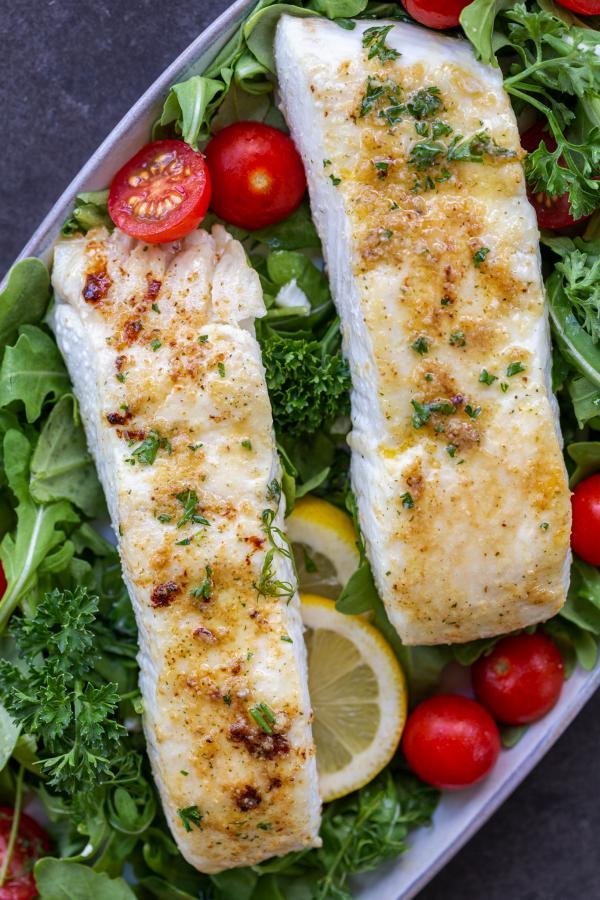 Baked Halibut on a plate with herbs and greens. 