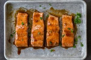 Baked salmon on a baking sheet with teriyaki sauce.