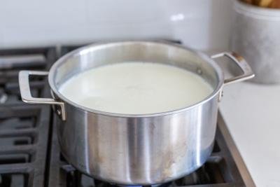 Pot of milk on a stove top.