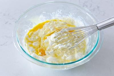 Sour cream and eggs whisked in a bowl.