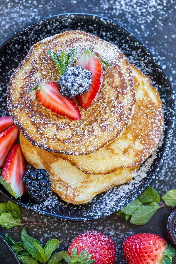 Pancakes on a plate with berries and powdered sugar