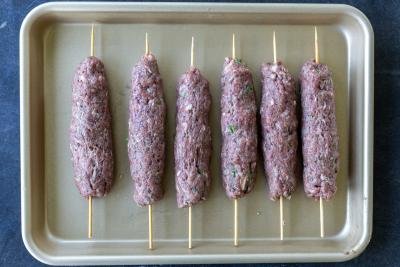 Uncooked All the ingredients for Beef Kafta Kabobs on a baking sheet.