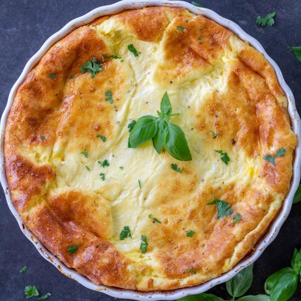 Crustless Quiche in a pan with herbs around it.