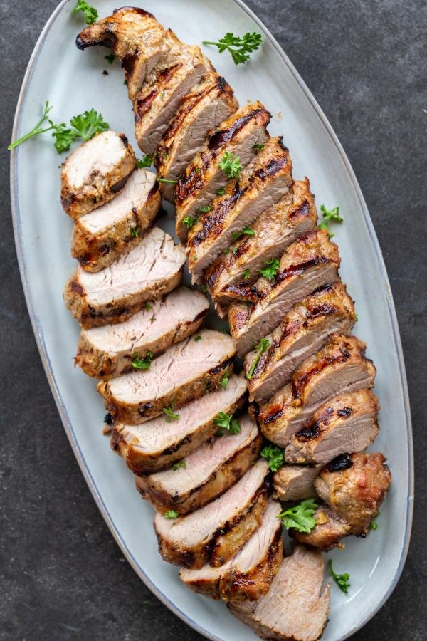 Grilled pork tenderloin sliced up on a plate. 