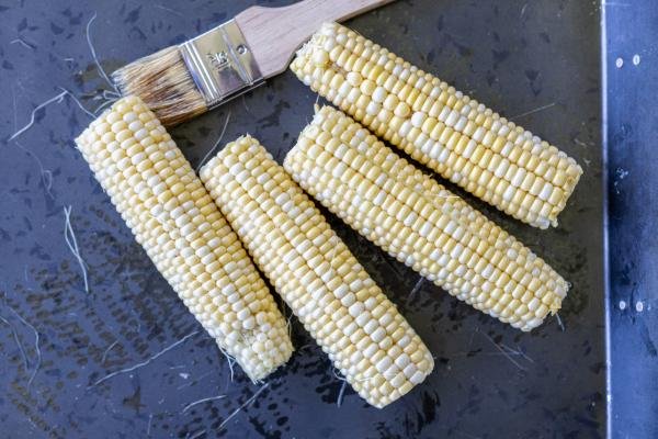 Corn with oil brush on a tray.