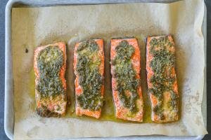 Baked salmon with pesto on a baking sheet.