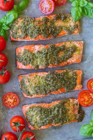 Pesto Salmon with tomatoes and basil on a baking sheet.