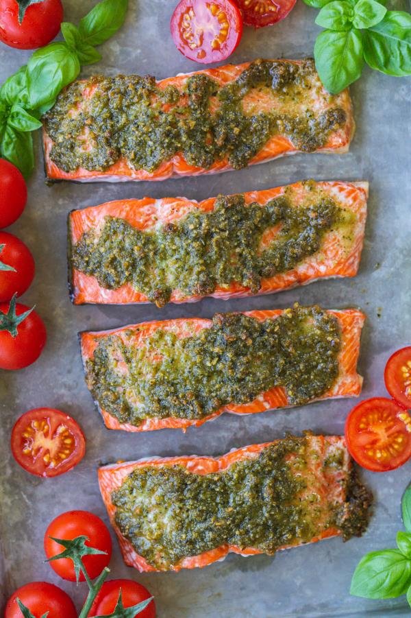 Pesto Salmon with tomatoes and basil on a baking sheet. 