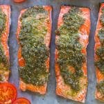Pesto Salmon with tomatoes and basil on a baking sheet.