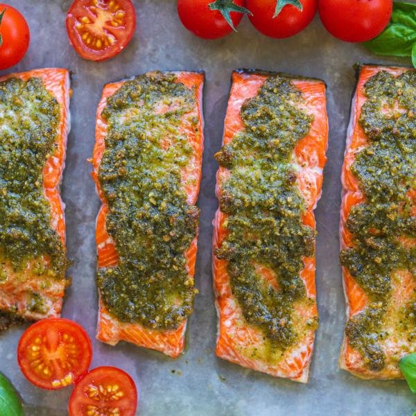 Pesto Salmon with tomatoes and basil on a baking sheet.