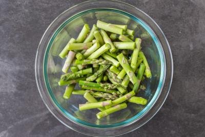 Asparagus cut into pieces in a bowl.