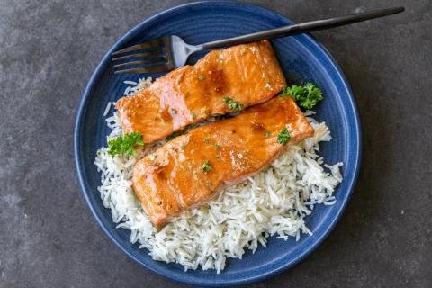 Baked salmon on top of rice on a plate.