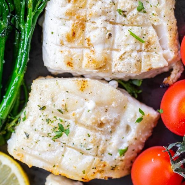 Grilled cod on a pan with veggies.