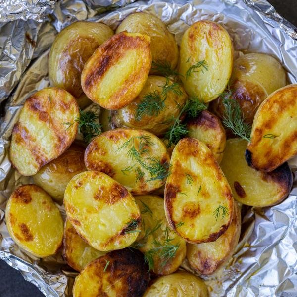 Grilled potatoes on foil with dill.