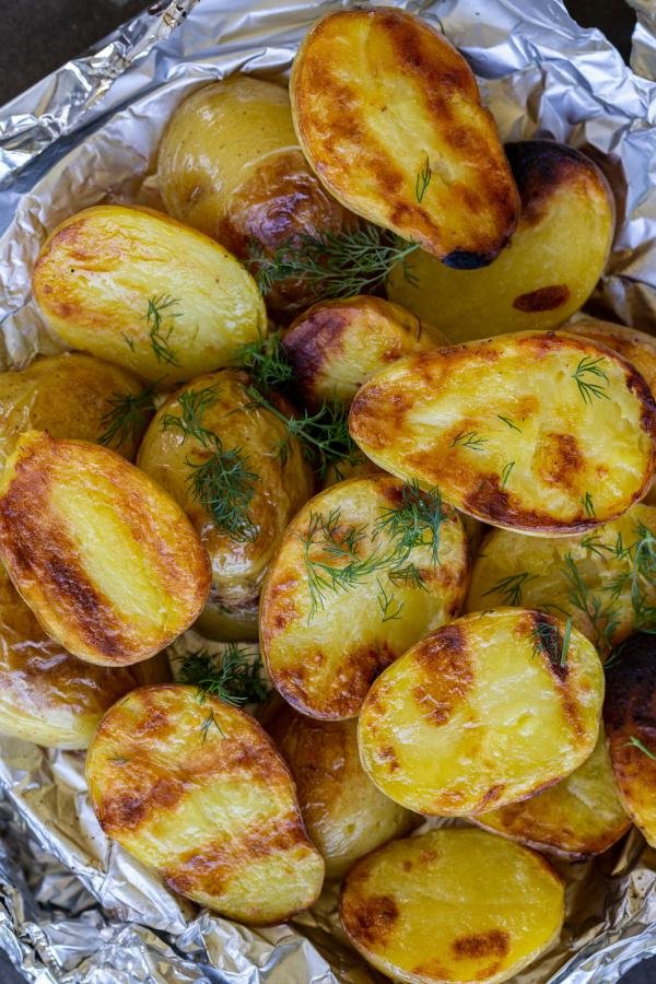 Grilled potatoes on foil with dill.