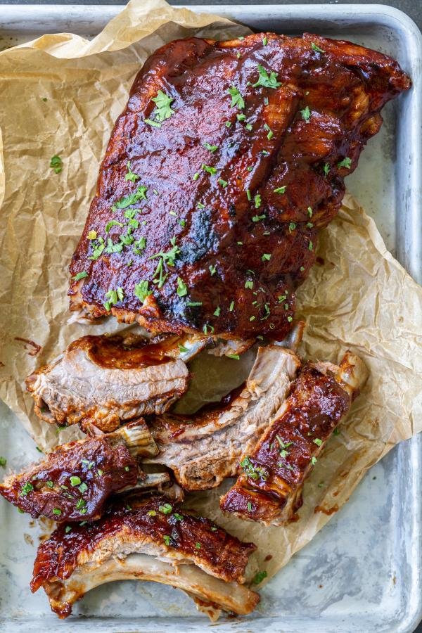 Cut BBQ ribs on a pan with herbs on top. 