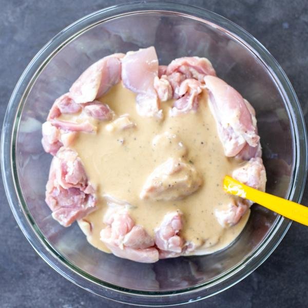 Chicken with marinade in a bowl.