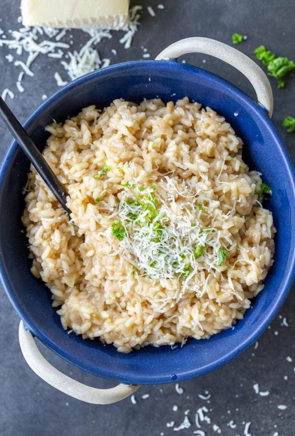 Parmesan risotto in a bowl with cheese and herbs. 