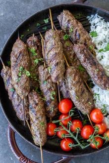 Beef Kafta Kabob on a pan with tomatoes with rice.