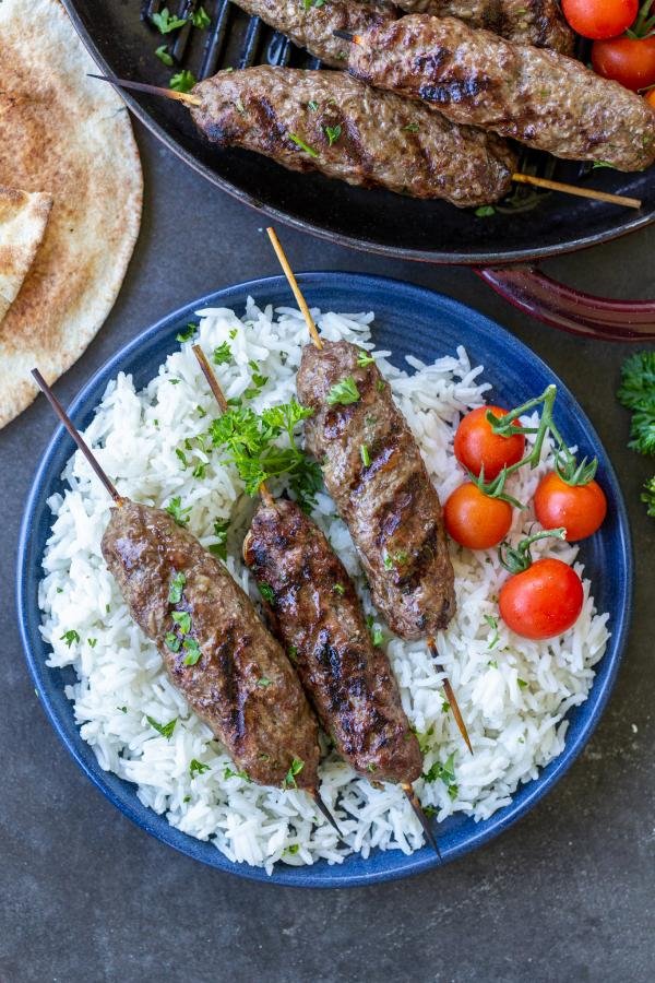 Beef Kafta Kabob on a pan with tomatoes with rice.